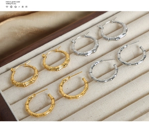 Detail of bamboo joint textured hoop earrings in gold and silver on a jewelry tray