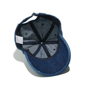Detail view of denim baseball cap interior showing lining, seams, and metal buckle adjustment
