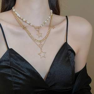 Detail shot of multi-layer star and pearl pendant necklace on a female model collarbone