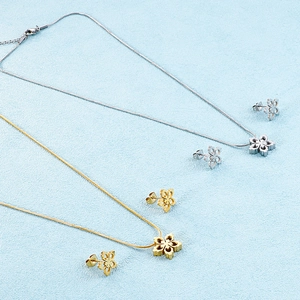 Detailed view of hollow snowflake pendants on gold and silver snake chains with studs