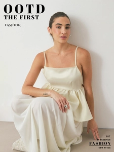Detail of cream satin camisole top showing smooth silk texture and ruffled hemline