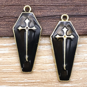 Macro shot of gothic coffin pendants with black enamel and gold cross details