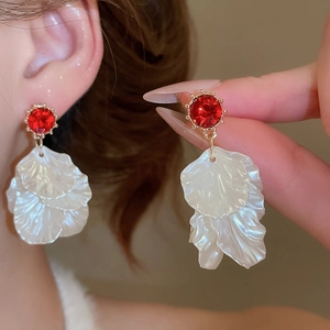 Detailed close-up of pearl petal tassel earrings with red rhinestones on a female model