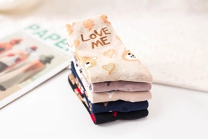 Detail of five pairs of cotton socks featuring cartoon dog motifs and heart patterns
