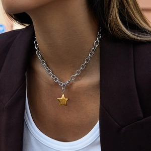 Close-up of a silver chain necklace with a gold star pendant on a female model
