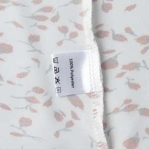 Détail du tissu floral 100% polyester avec coutures blanches et étiquette de soin