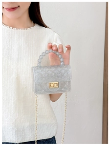 Detail of silver glitter PVC jelly bag with pearl handle and golden chain strap for women