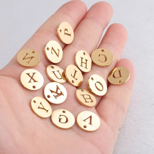 Vue rapprochée de pendentifs alphabet en acier doré dans la main pour la taille