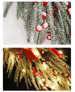 Detail of Christmas pine swag with red berries and warm LED lights for festive decor