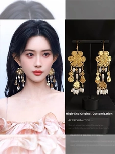 Detailed view of gold flower earrings with hanging pearls and tassels on model