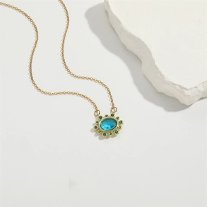 Luxurious gold necklace with an oval blue birthstone and green crystal halo
