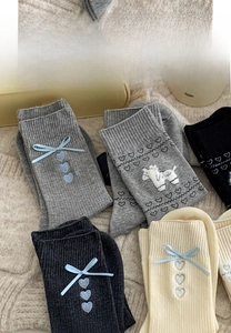 Detail von grauen und beigen Baumwollsocken mit blauen Schleifen und Herzstickerei