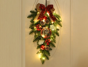 Détail d'une couronne de Noël avec lumières LED, pommes de pin et signe Holly