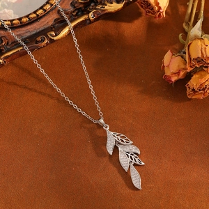 Macro detail of silver leaf pendant with micro-inlaid diamonds on an artistic background
