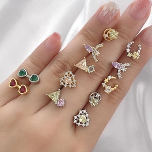 Macro view of colorful geometric stud earrings held in hand against white silk