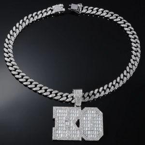 Macro detail of silver iced-out 100 pendant and crystal-studded Cuban link necklace
