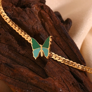 18K gold plated stainless steel butterfly pendant on NK chain over wood background