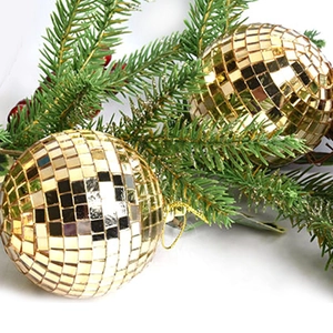 Golden mirror disco ball ornament hanging on Christmas tree with festive pine and berries