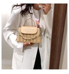 Detail of beige PU leather crossbody bag with decorative thick metal chain and logo