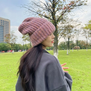 Outdoor shot of a thick pink knit beanie showing warm chunky texture and rolled edge
