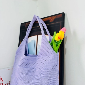 Detail of purple knitted tote bag featuring hollow weave texture and floral decor