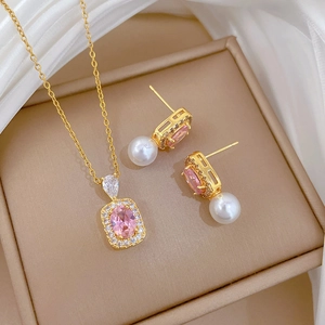 Elegant gold jewelry set with pink stones and pearls displayed on white silk fabric