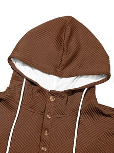 Dettaglio macro del tessuto jacquard marrone con bottoni in legno e coulisse bianche