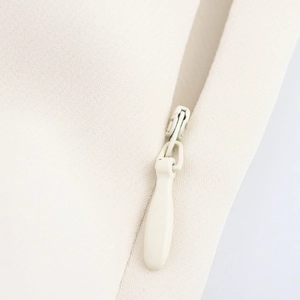 Chic beige sleeveless dress with shoulder pads and a concealed back zipper detail