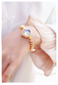 Detailed close-up of a gold luxury women watch with rhinestones and white roman dial