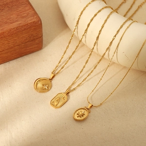 Trois colliers en acier inoxydable plaqué or 18K avec pendentifs étoile et lune sur fond beige
