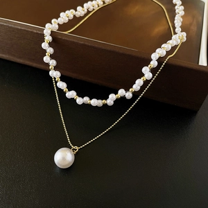 Détail d'un collier de perles double couche avec chaîne dorée sur boîte à bijoux
