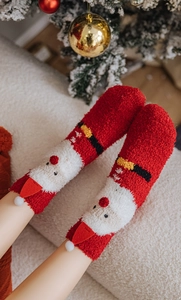 Close-up of fluffy red Christmas socks with Santa Claus design and soft pom-pom details