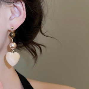 Detail showing vintage heart drop earring with tiger eye stone and pearl on a model