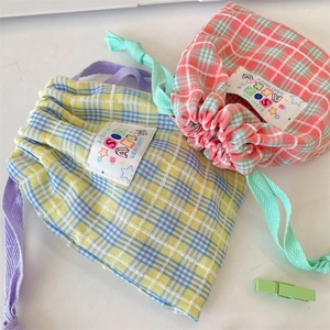 Close-up of colorful plaid drawstring storage pouches with decorative sewn tags