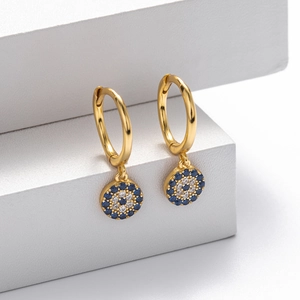 Macro detail of gold S925 sterling silver evil eye earrings with blue and white pavé stones