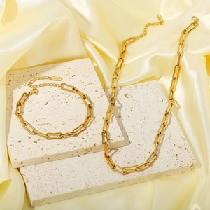 Gold stainless steel paperclip chain necklace and bracelet set on a silk backdrop