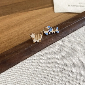Macro shot of cute cartoon kitten and fishbone earrings with enamel texture and fine details