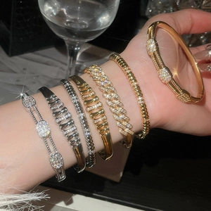 Close-up of stacked 18K gold and silver wave bangles with sparkling crystals on wrist