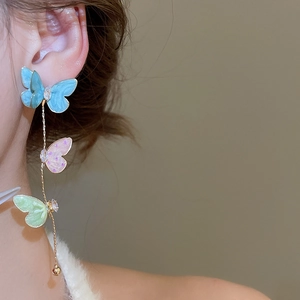 Macro shot of three-color gradient enamel butterfly earrings with gold tassel chains