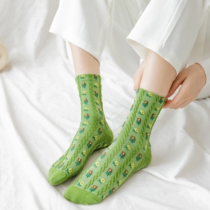 Women's green crew socks with yellow flowers and brown bear patterns shown on a model