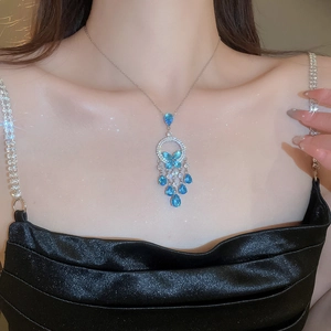 Close-up of elegant silver necklace with blue butterfly pendant and zircon tassels