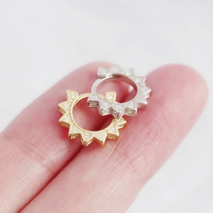 Macro view of small geometric S925 silver hoop earrings with spikes and crystals