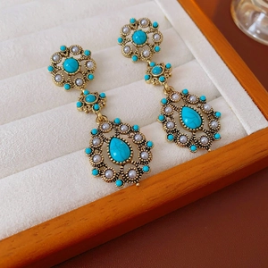 Detail of vintage gold earrings with green stones and pearls in a velvet jewelry box
