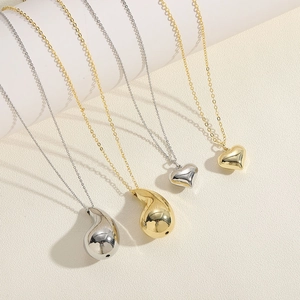 Minimalist gold and silver heart and waterdrop pendant necklaces on white display pedestals