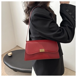 Detail view of a classic red leather underarm bag with gold lock and sleek finish