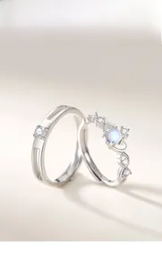 Macro shot of silver plated moonstone couple rings for men and women on warm beige surface