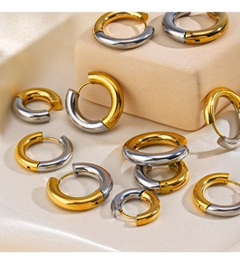 Macro detail of mixed gold and silver chunky hoop earrings on elegant silk background