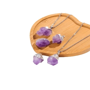 Anhänger aus natürlichem Amethyst-Kristall mit vergoldeter Fassung auf Holztablett