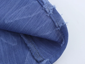 Détail du tissu jacquard denim bleu montrant les bords effilochés et le tissage