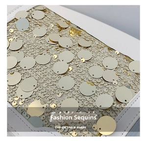 Dettaglio di paillettes dorate scintillanti su borsa tote in pelle bianca da donna
